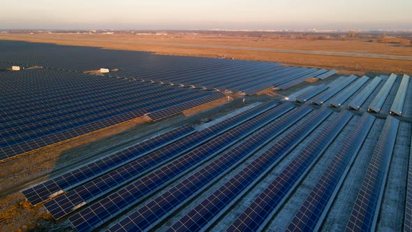 Aerial Drone View of Large Solar Panels at a Solar Farm at Bright Sunset in Early Winter alt