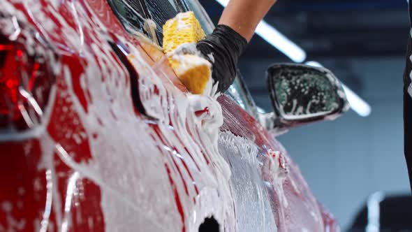 Auto Cleaning Service  Man Worker Cleaning the Car Surface with a Yellow Sponge alt
