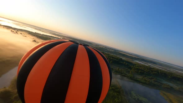 Dynamic aerial shot of black and orange hot air balloon