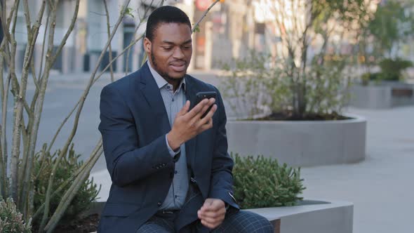 Irate Annoyed Angry African American Black Businessman Holding Smartphone Looking at Phone Screen alt