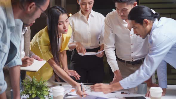 Asian young business people have discussion meeting and brainstorming overwork in office at night. alt