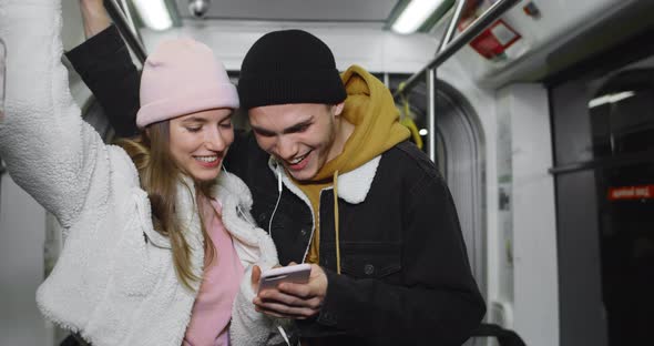 Young Guy and His Girlfriend Using Smartphone and Laughing While Looking at screen.Cheerful Couple alt
