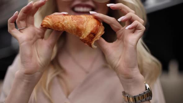 Close-up Smiling Woman Tearing Off Fresh Appetizing Croissant By Hand Having Positive Emotion