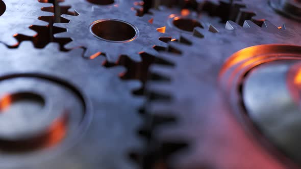 Closeup on slowly rotating dark metallic gears. Clockwork machinery in motion.
