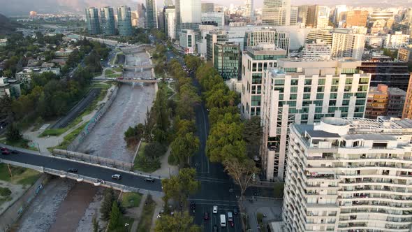 Aerial dolly out of cars driving in Andres Bello avenue surrounded by trees, Sanhattan skyscrapers a alt