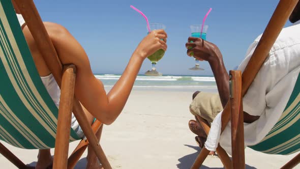 Couple toasting glasses of cocktails at beach 4k alt