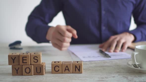 Motivational Phrase Yes You Can Put It On Your Desktop. A Business Man Works With Papers But Nothing alt