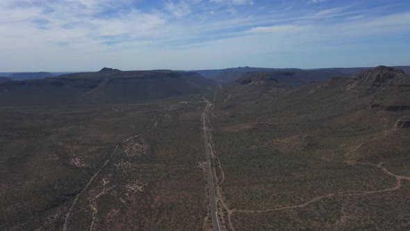 Desert Road Across Arid Mountain Terrain with Bush and Cactus