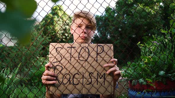 a Young Caucasian Teenager Man in a Blue Shirt Sits Holding a Cardboard Box on Outstretched Hands in alt