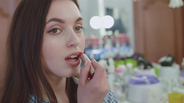 Pretty Girl Makes-up, Applies Red Lipstick on Lips and Smiles alt