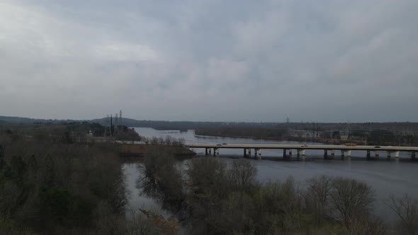 View of bridge over river in autumn. Power station, mountains, and cloudy sky.