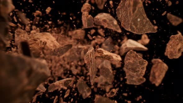Super Slow Motion Detail Shot of Falling Raw Chocolate Chunks on Black Background at 1000Fps alt