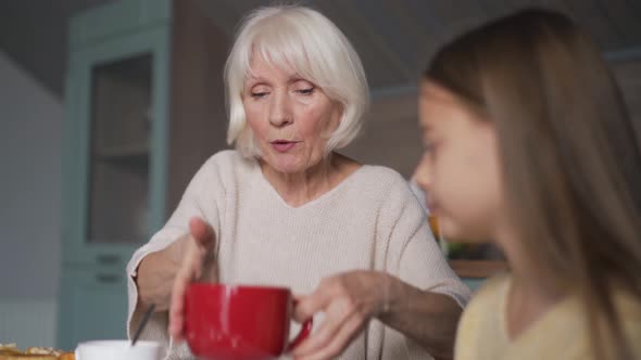 Happy grandmother and granddaughter having breakfast alt