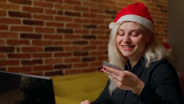 Female person input credit card information to laptop at home indoors. Attractive young adult woman alt