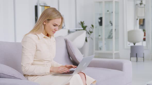 A young girl getting good news by chatting in a laptop sitting on the couch alt