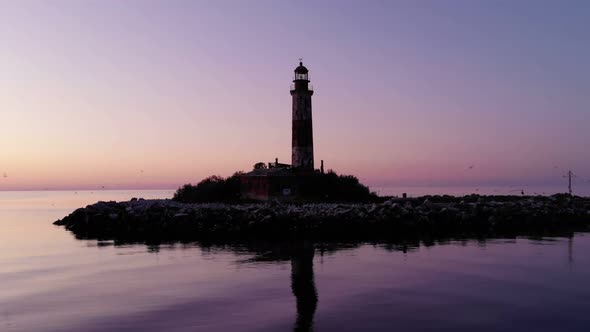 Old lighthouse on little island, cinematic orbiting shot after sunset