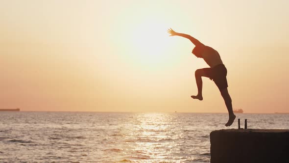 Young Man Jumping From Sea Pier and Doing Backflip During Beautiful Sunrise Super Slow Motion alt
