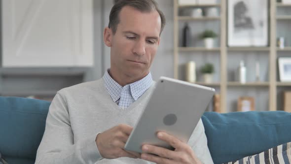 Online Shopping on Tablet By Middle Aged Man Sitting on Couch alt