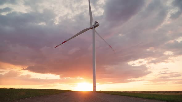Time lapse windmill is spinning against the backdrop of a beautiful cloudy sky and sunset. alt