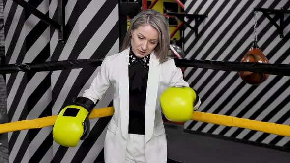 Young Business Woman in a White Suit and Boxing Gloves in a Boxing Ring