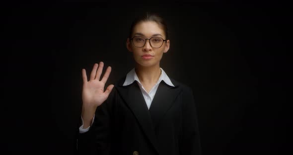Serious Asian Woman in Business Clothes Waves Her Hand alt