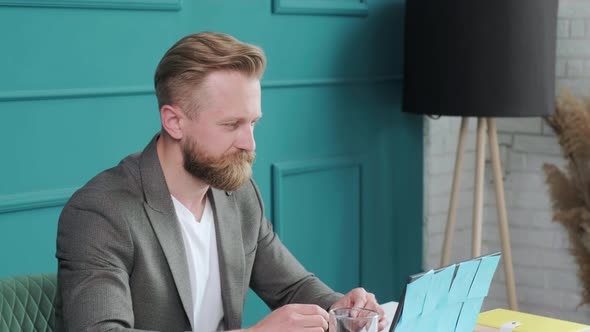 Bearded Man Comfortable at His Desk in Underwear and Jacket Working Remote alt
