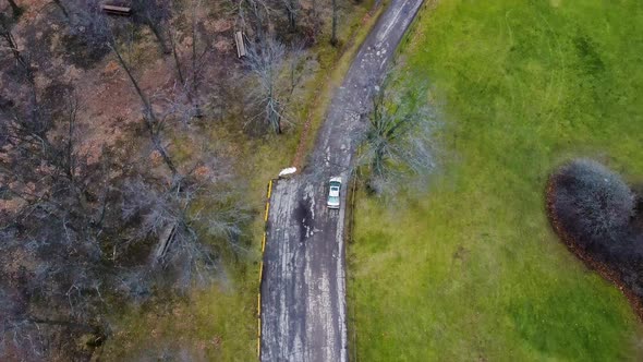 Silver car driving through road in rural landscape. Aerial. alt