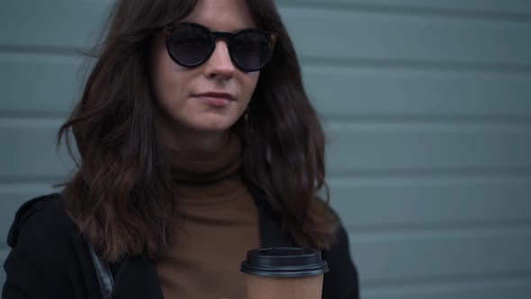 Slow Motion Tilt Up of Woman Taking Off Sunglasses Smiling with a Cup of Coffee