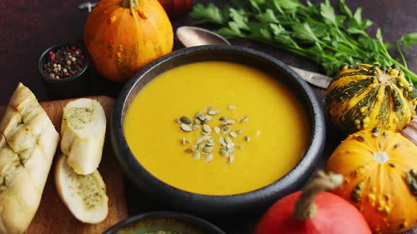 Delicious Pumpkin Soup with Cream Sumflower Seeds and Garlic Toasts on Dark Rusty Background