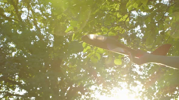 the Hand Holds a Toy Plane Against the Background of the Sun and Emits Flight the Image of an alt