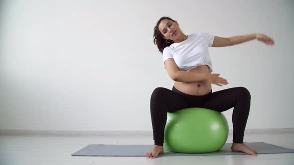 Young Pregnant Woman Goes in for Sports in a Living Room alt