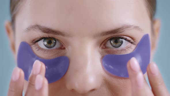 Close Up of Beautiful Young Woman Touching Purple Eye Patches While Looking to Camera  alt