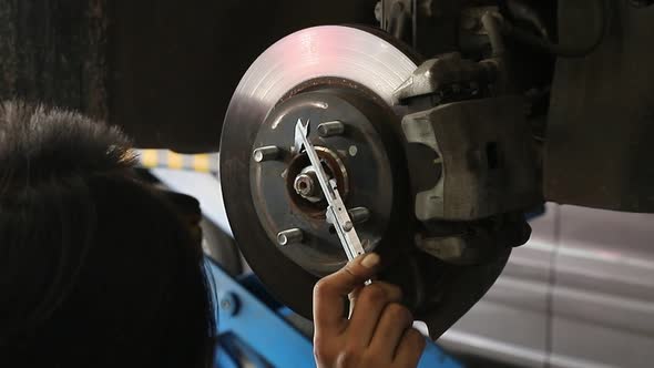 Car mechanic repairing wheel in auto repair service.