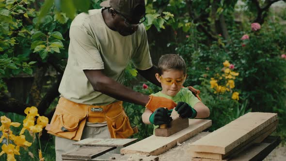 African American Carpenter Teaches Little Boy to Use Plane