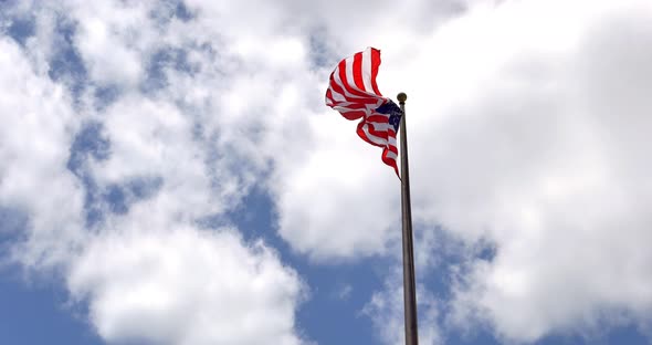 4K American flag - star and stripes floating over a cloudy blue sky