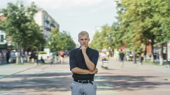 Tiltdown Time Lapse of Attractive Young Businessman Standing Outdoors in Busy Street with Pensive alt