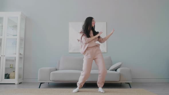 Young funny caucasian woman with glasses joyfully dancing and at home.
