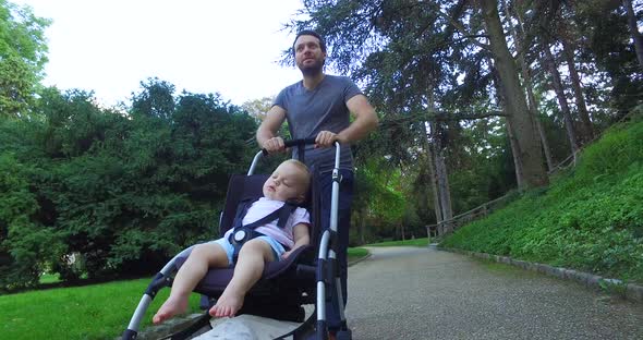 Father walking in park with his son in pram