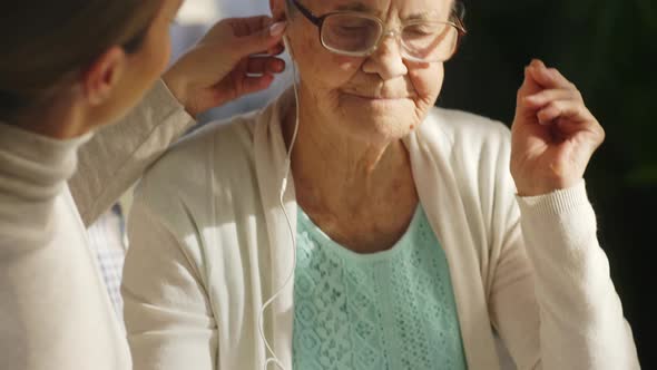 Woman Teaching Grandmother How to Watch Video on Tablet