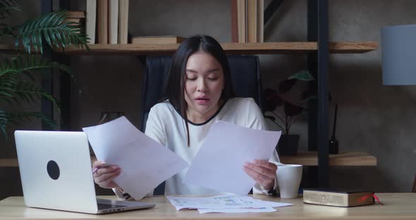 Asian Business Woman From Fatigue Closes the Laptop Puts Documents Aside and Leans on the Back of alt