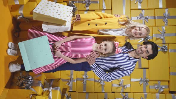 a Fashionable Family Holding Bags with New Clothes in Their Hands Poses for the Camera in an Evening alt