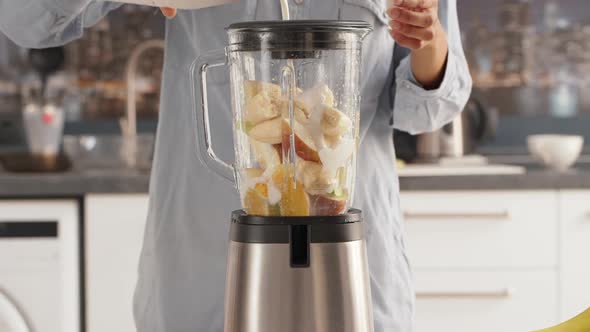Close Up Footage of Female Adding Milk to Blender with Pieces of Fruits to Make Smoothie in alt