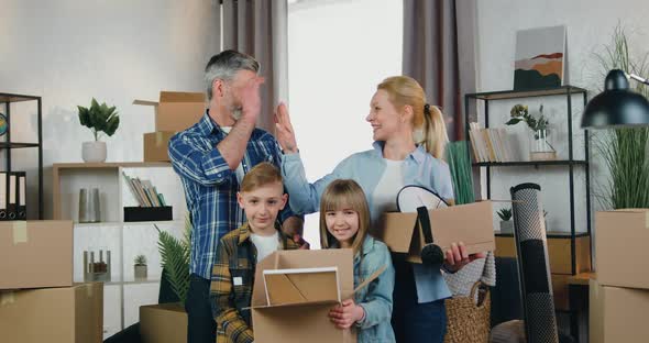 Couple Giving High Five and Posing on Camera Together with Their Kids with Cartons alt