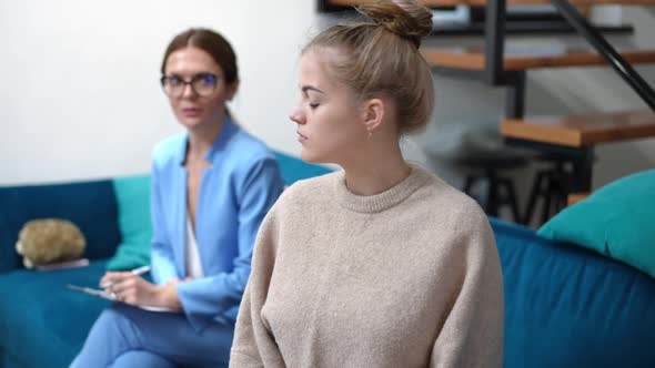 Dissatisfied Angry Teenage Girl Looking Back at Blurred Therapist Turning to Camera Sighing alt