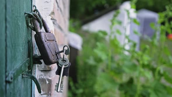 Keys are Swinging in the Old Padlock That is Hanging on the Green Wooden Door alt