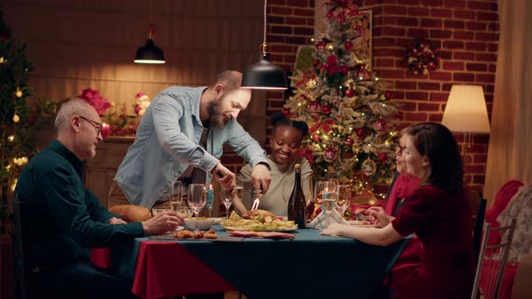 Confident Husband Cutting Roasted Chicken While Celebrating Christmas alt