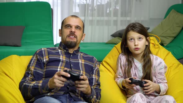 father and daughter playing gamepads together at home alt