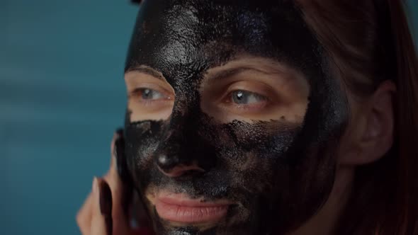 Young 30s Woman with Black Hoop on Head Applying Black Cosmetic Mask on Her Face. Woman Beauty alt