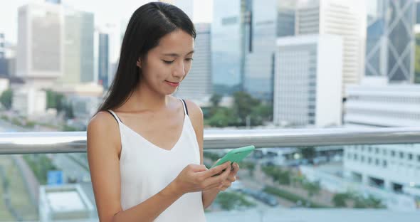 Woman typing on smart phone in city alt