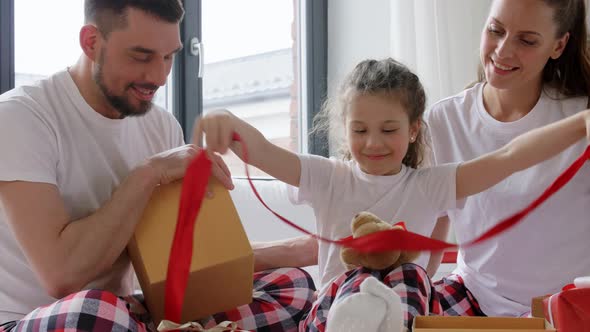 Happy Family with Christmas Gifts in Bed at Home alt
